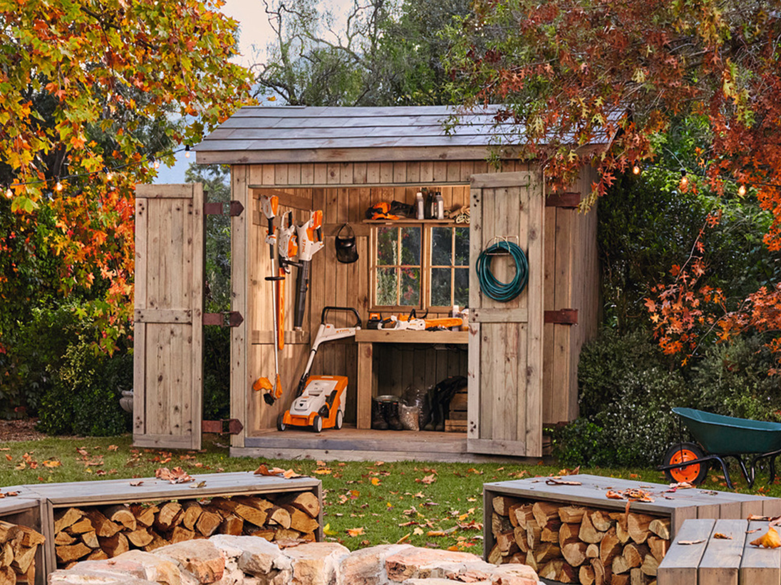 Herbstgarten mit Schuppen voller STIHL Gartengeräte und gemütlicher Lagerfeuerstelle