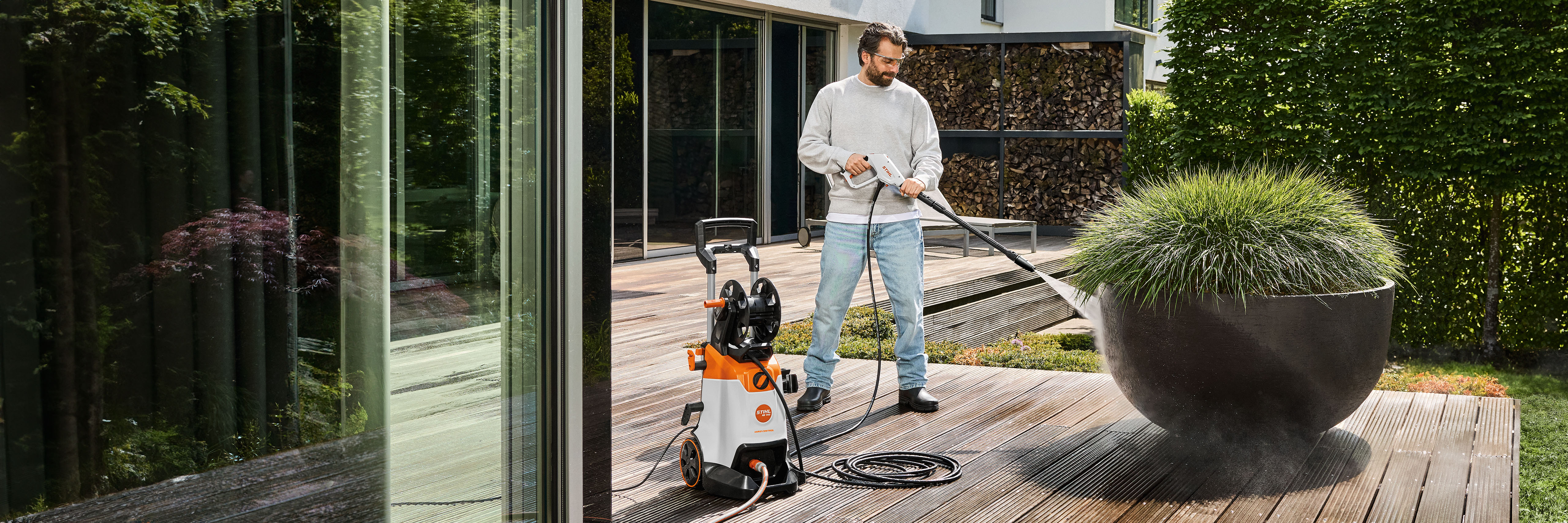 Ein Mann reinigt das Holzdeck seiner Veranda mit dem STIHL RE 140.