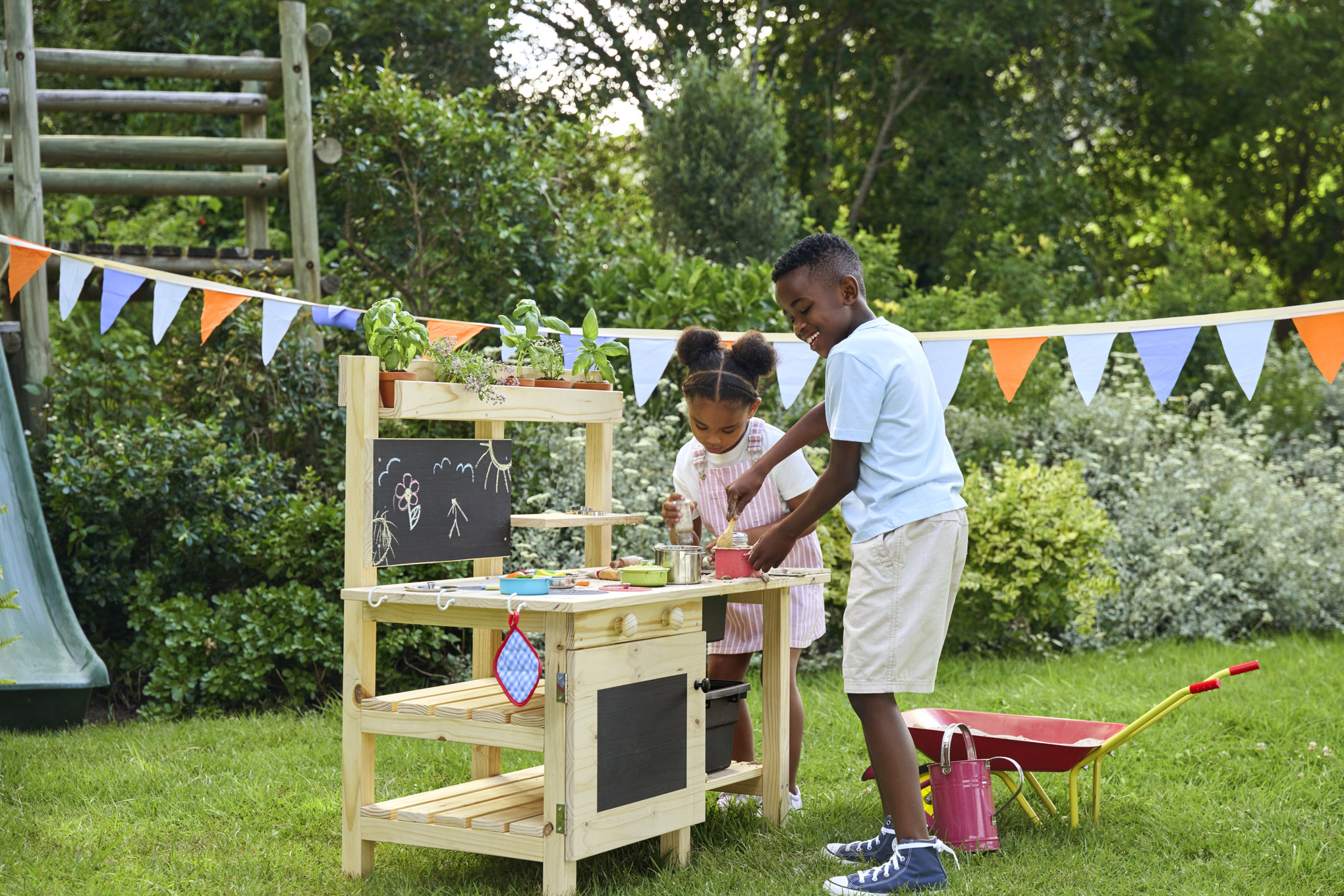 Mädchen und Junge im Garten und beim Kochen in ihrer neuen DIY Matschküche