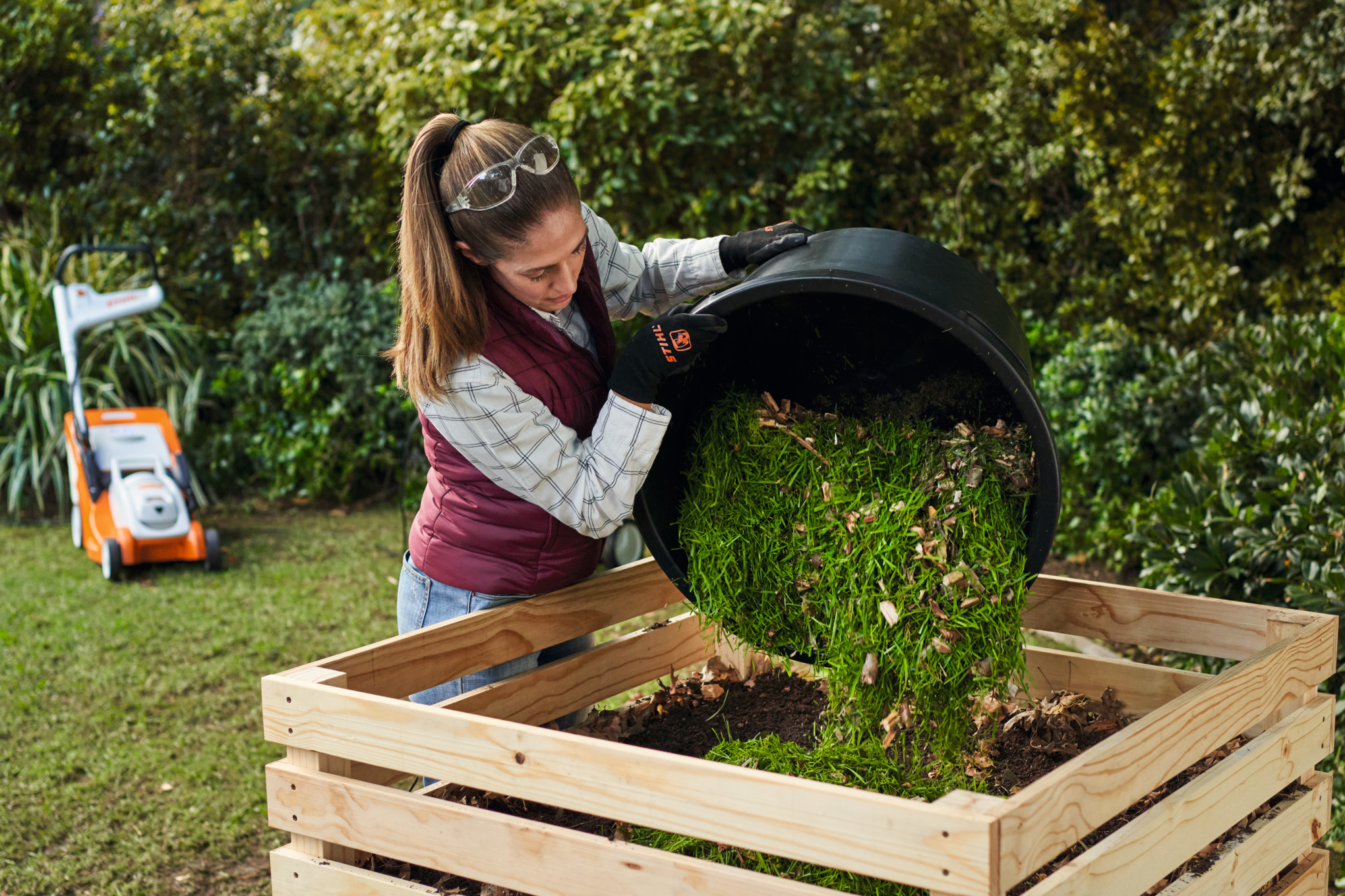 Frau kippt Kompost in einen Komposter