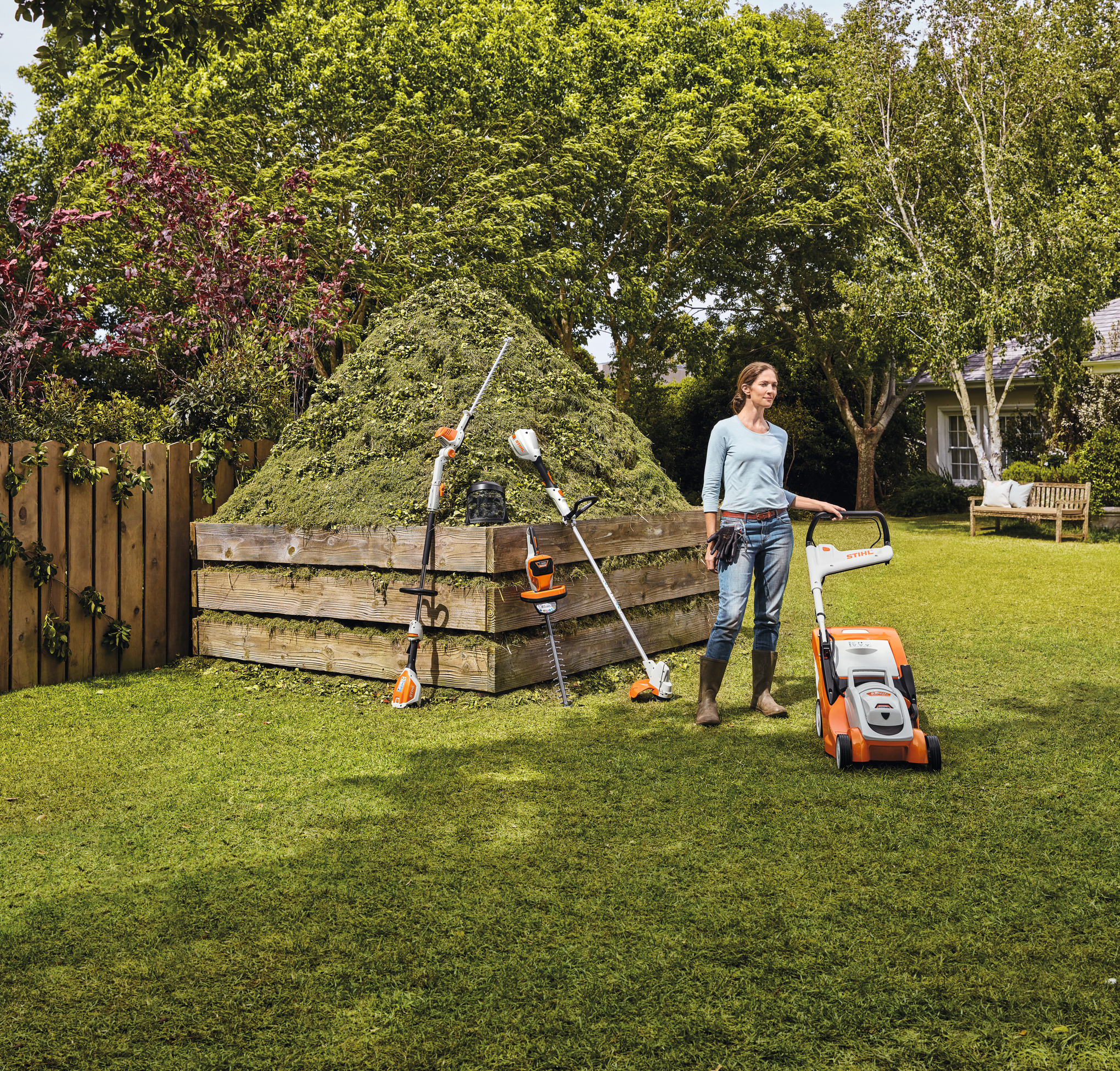 Frau steht mit STIHL Produkten zufrieden im Garten.