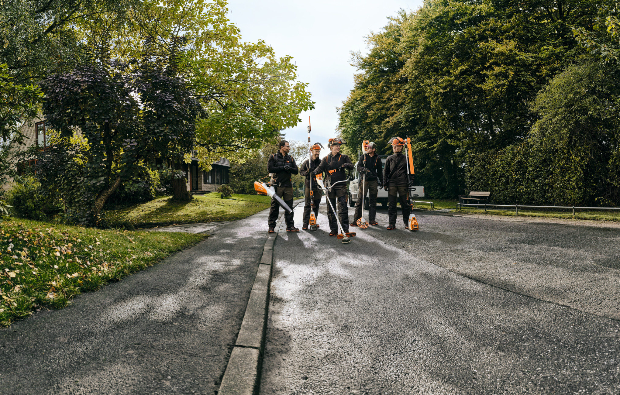 Fünf STIHL Profis laufen mit Akku-Geräten eine Straße entlang