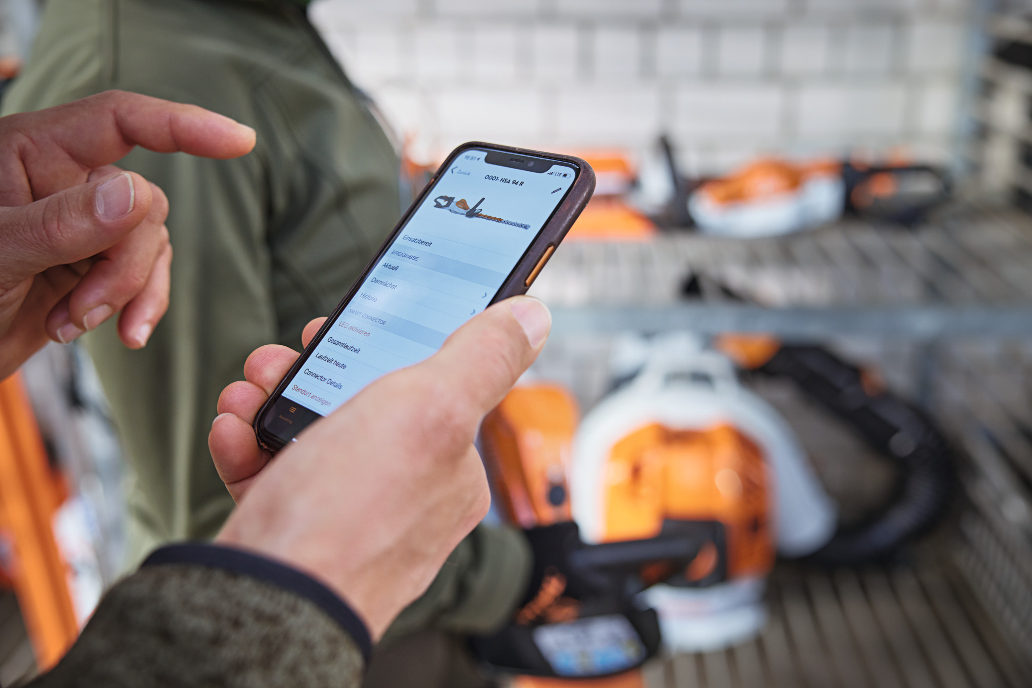 Eine Person mit Smartphone schaut sich Motorsäge in STIHL connected App an