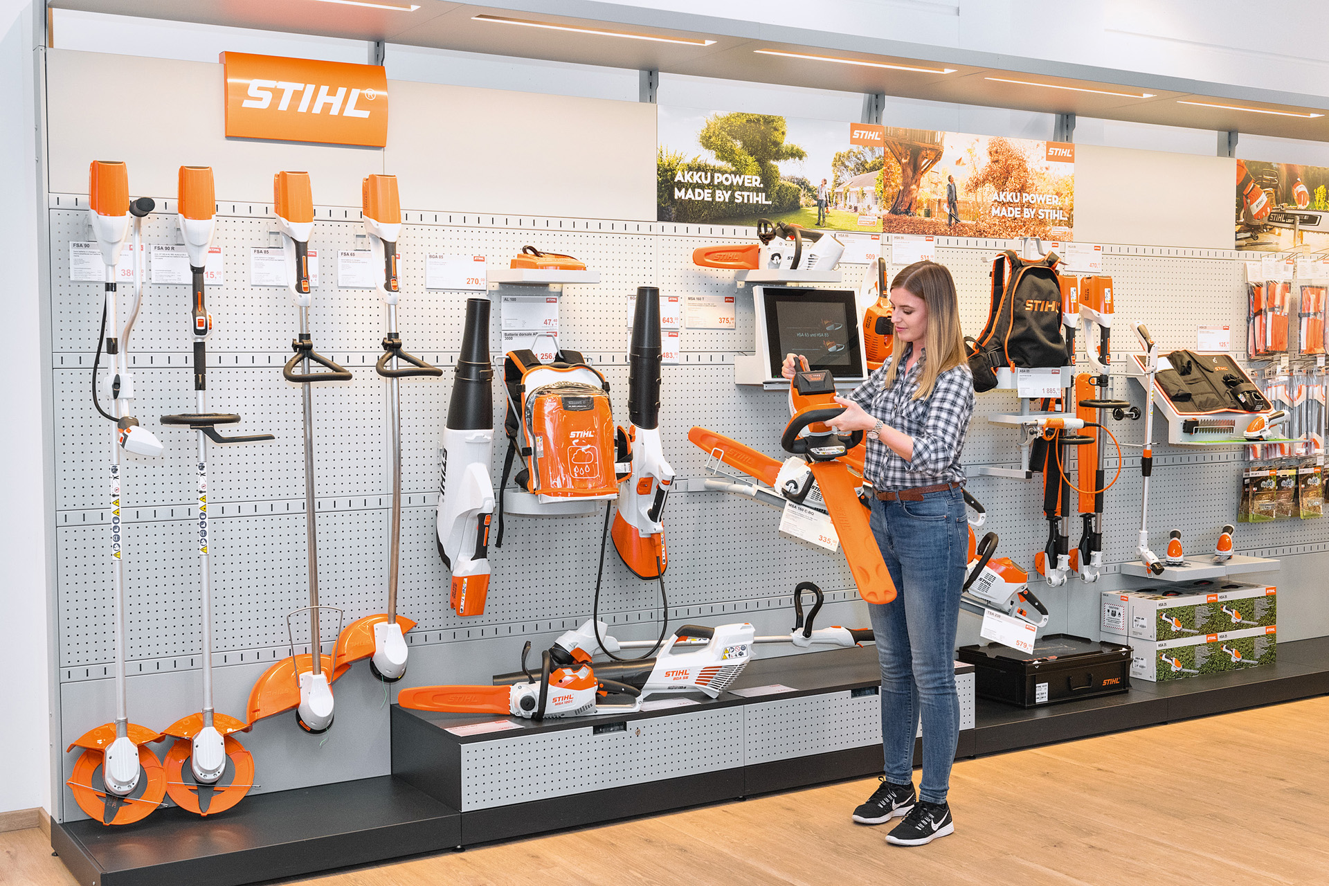 Junge Frau vor einem Verkaufsregal bei einem STIHL Fachhändler möchte eine STIHL Kettensäge kostenlos testen