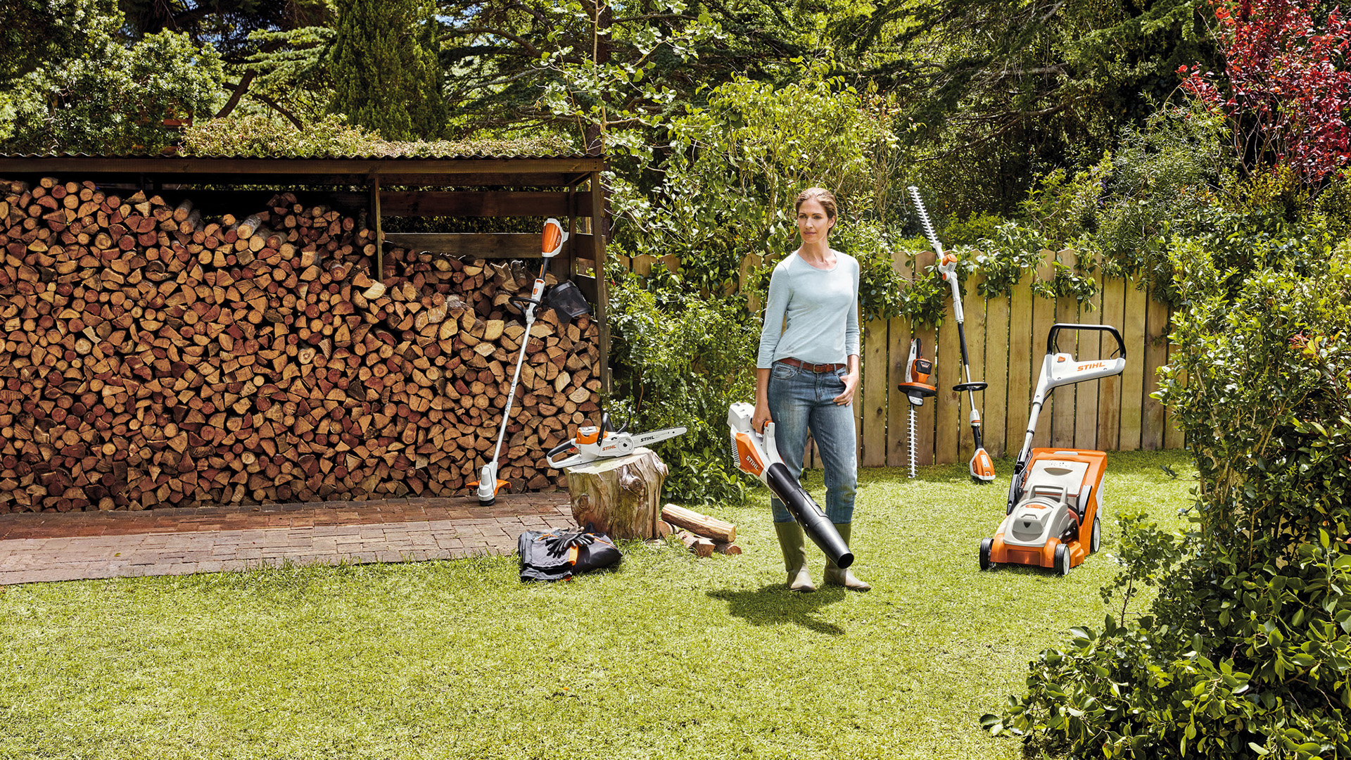 Frau steht im Garten vor einem Holzstapel mit den Geräten des AK-Systems 