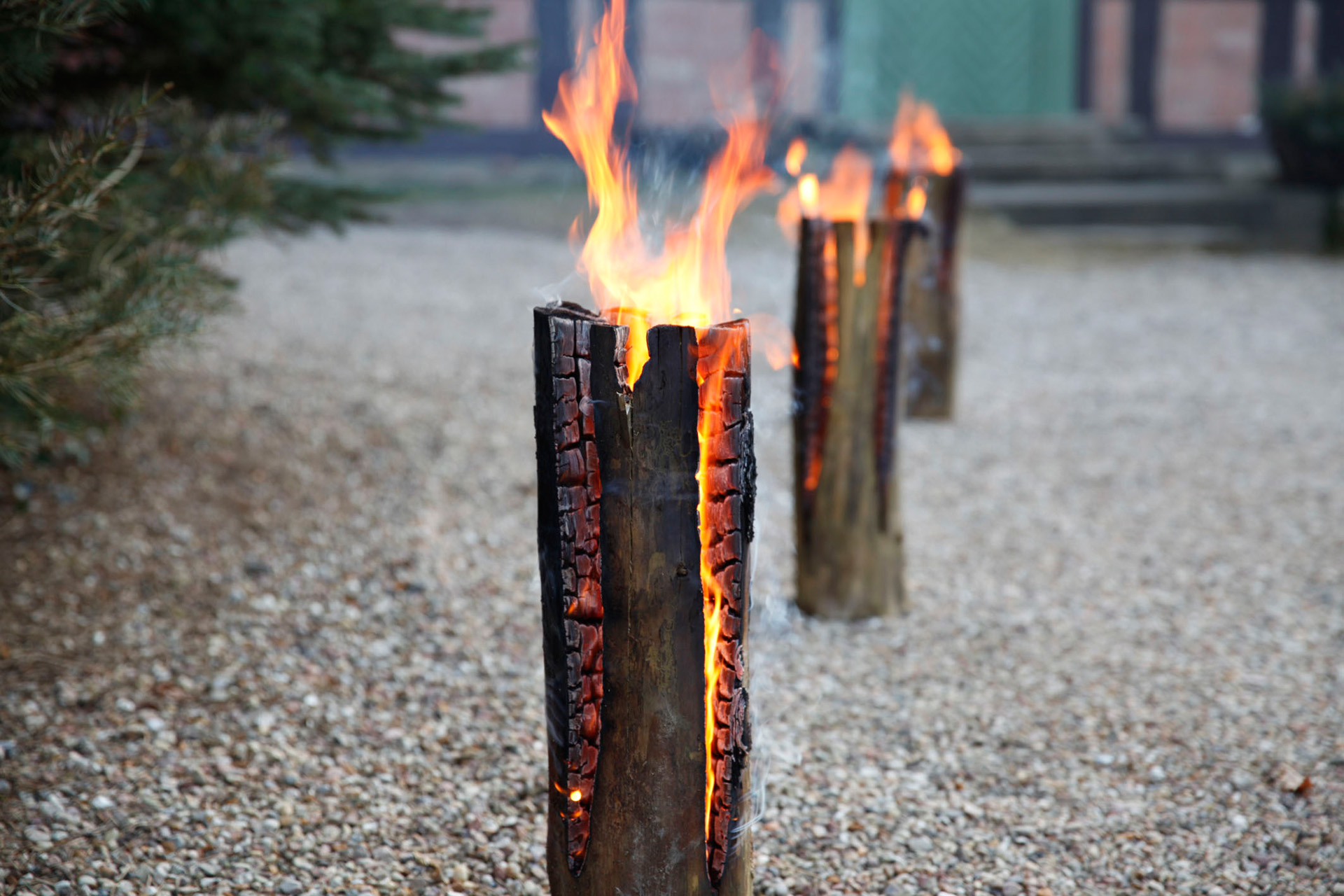 Drei brennende Schwedenfeuer zum Selbermachen auf einem Schotterweg