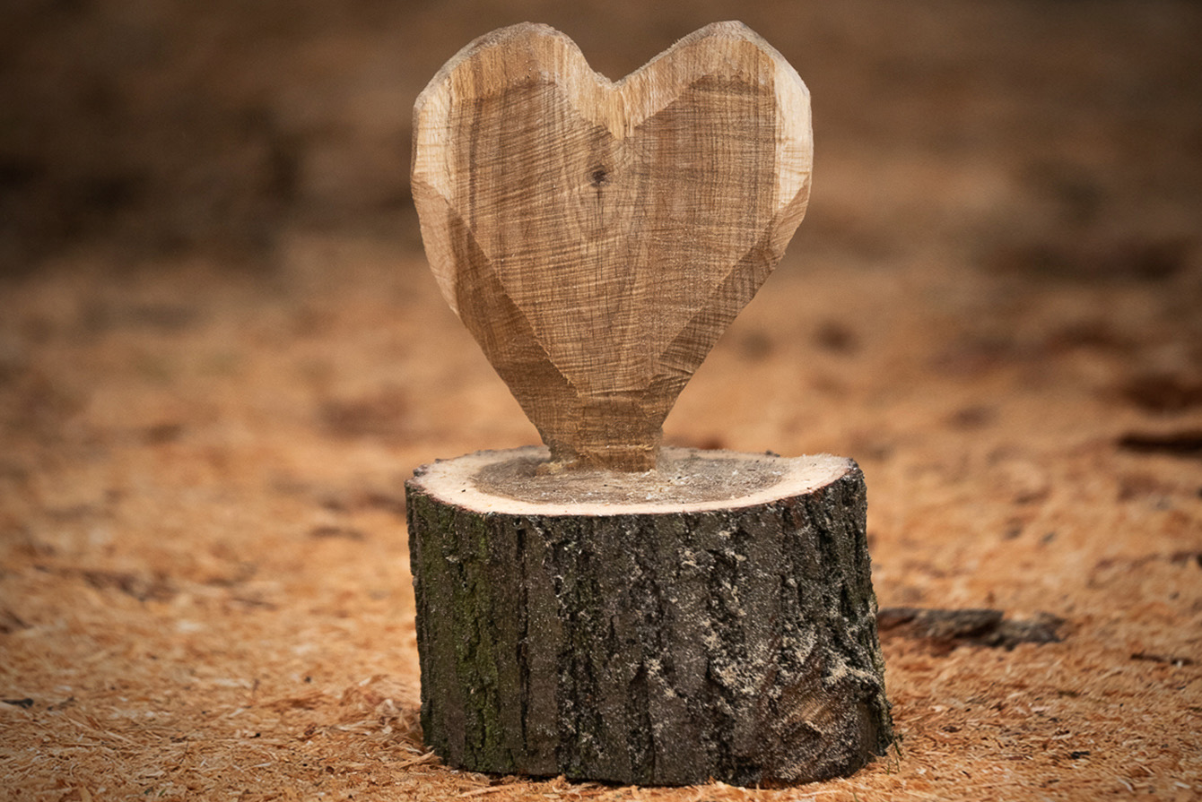 Herz aus Holz zum Selbermachen steht auf dem Boden zwischen Spänen