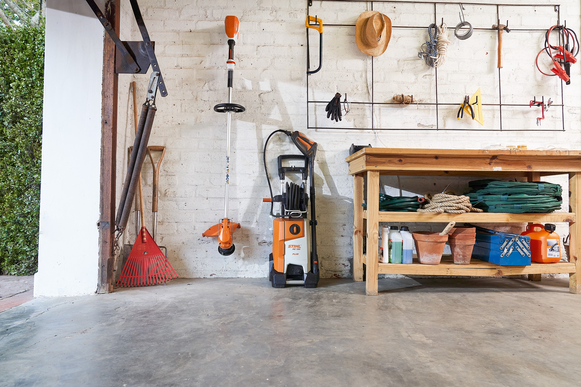 Ein STIHL Hochdruckreiniger und eine STIHL Akku-Motorsense lagern in einer Garage