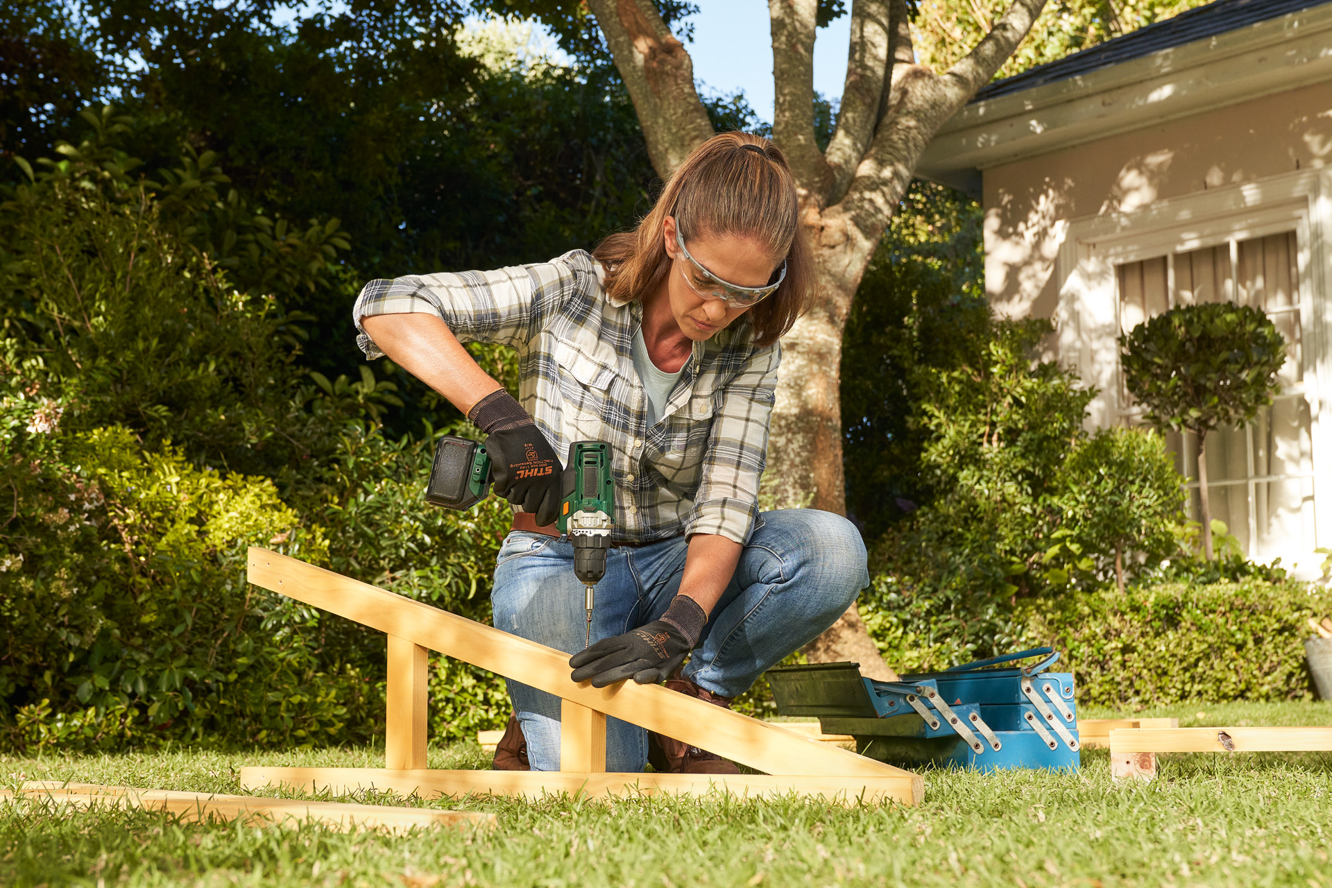 Person mit STIHL Schutzhandschuhen nutzt einen Akku-Schraubbohrer an einem Holzbalken