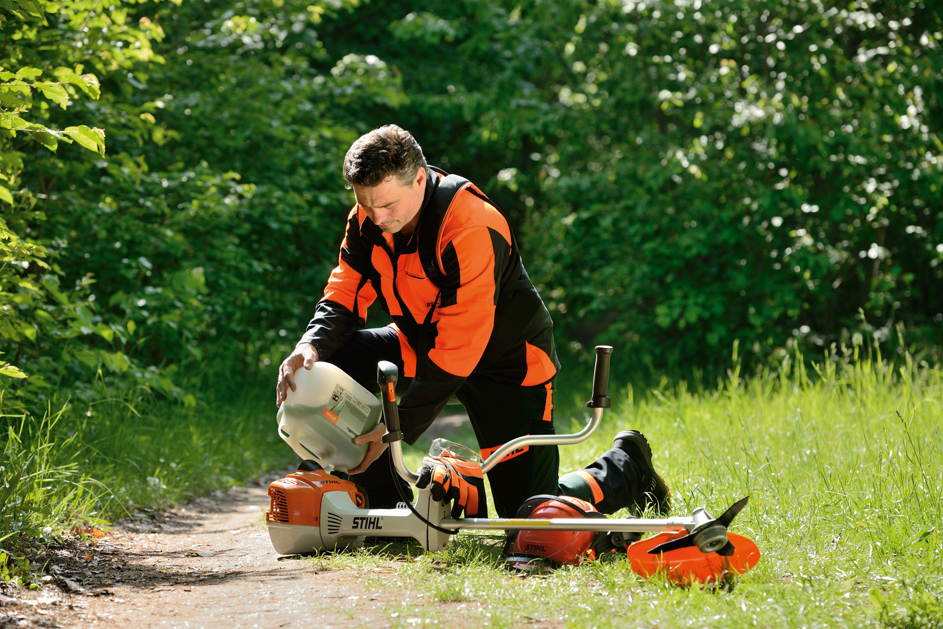 Mann betankt STIHL Motorsense mit einem Benzin-Öl-Gemisch