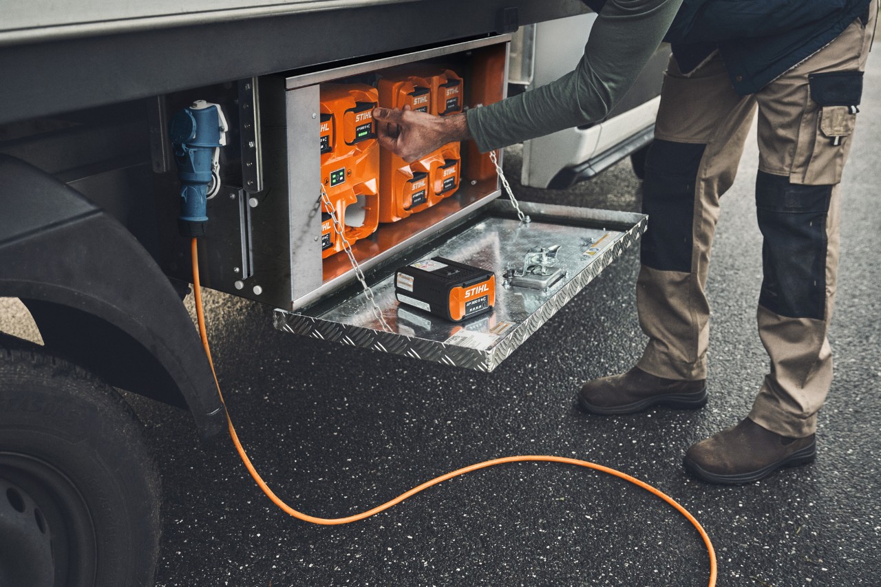 Ein Mann holt einen aufgeladenen STIHL Akku AP 500 aus der Ladebox 