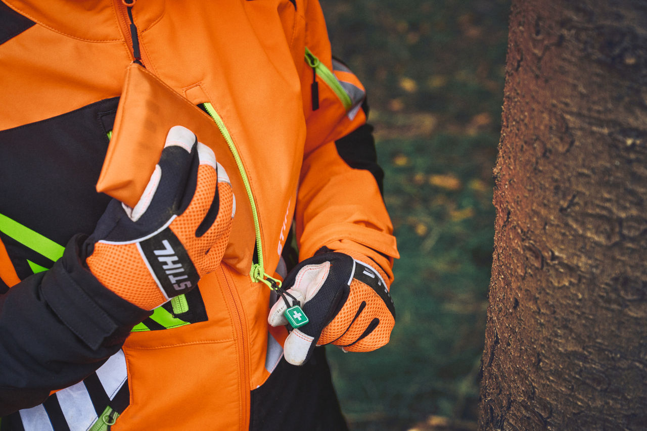 Nahaufnahme einer Person in STIHL ADVANCE FlexTEC mit ShellTEC Erste-Hilfe-Reißverschlussanhänger im Forst